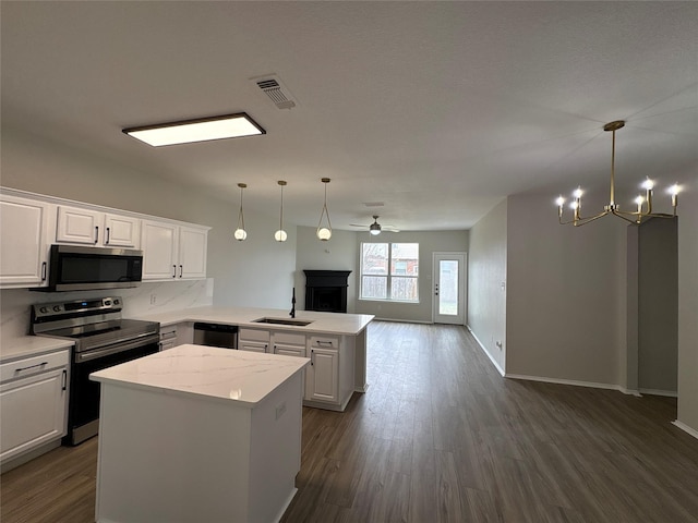 kitchen featuring appliances with stainless steel finishes, open floor plan, a center island, a peninsula, and a sink