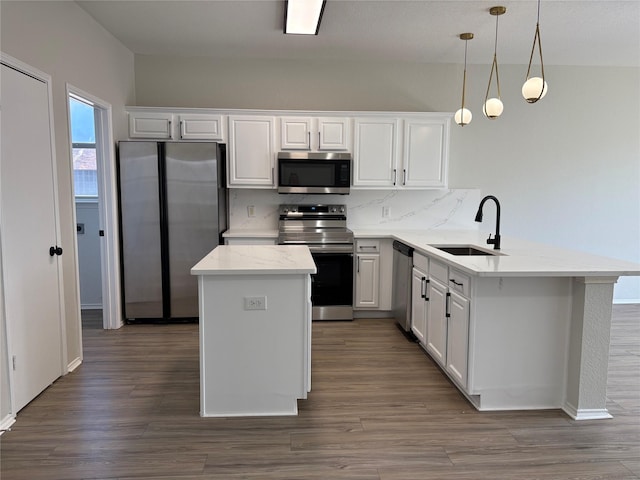 kitchen with dark wood-style floors, a kitchen island, a peninsula, stainless steel appliances, and a sink