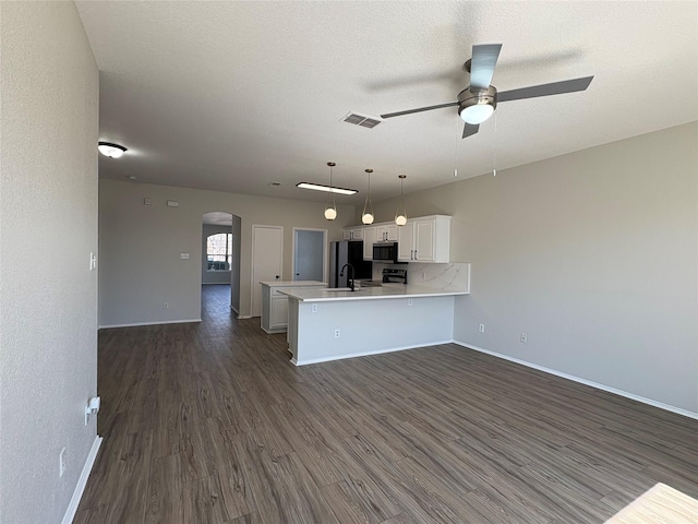 kitchen featuring arched walkways, light countertops, visible vents, open floor plan, and a peninsula