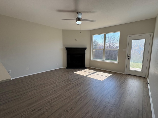 unfurnished living room with ceiling fan, baseboards, a fireplace with raised hearth, and dark wood-type flooring