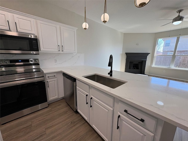 kitchen featuring tasteful backsplash, white cabinets, appliances with stainless steel finishes, wood finished floors, and a sink