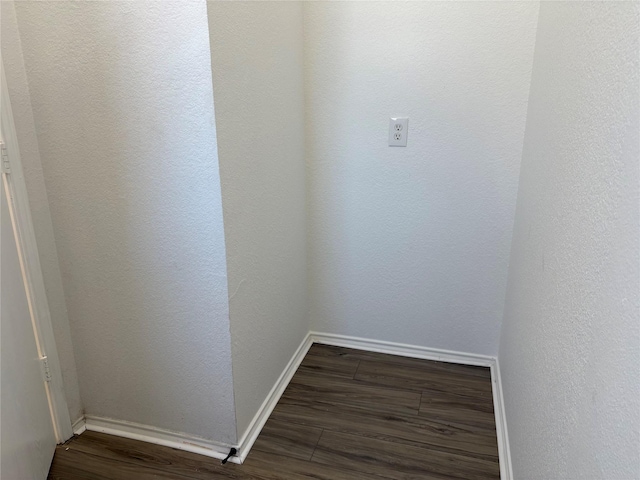 interior space with dark wood-style floors, a textured wall, and baseboards