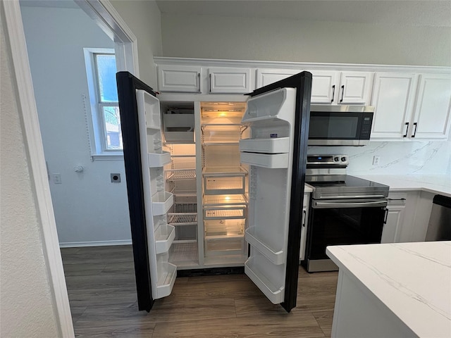 kitchen featuring white cabinets, dark wood finished floors, appliances with stainless steel finishes, light stone countertops, and backsplash