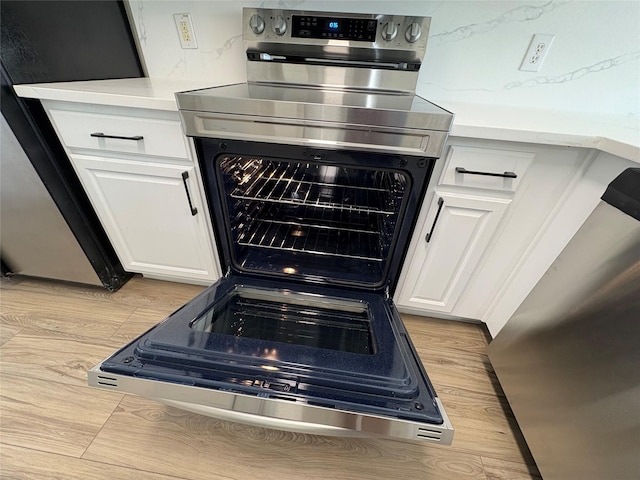 interior details with light countertops, electric range, decorative backsplash, white cabinetry, and light wood-type flooring