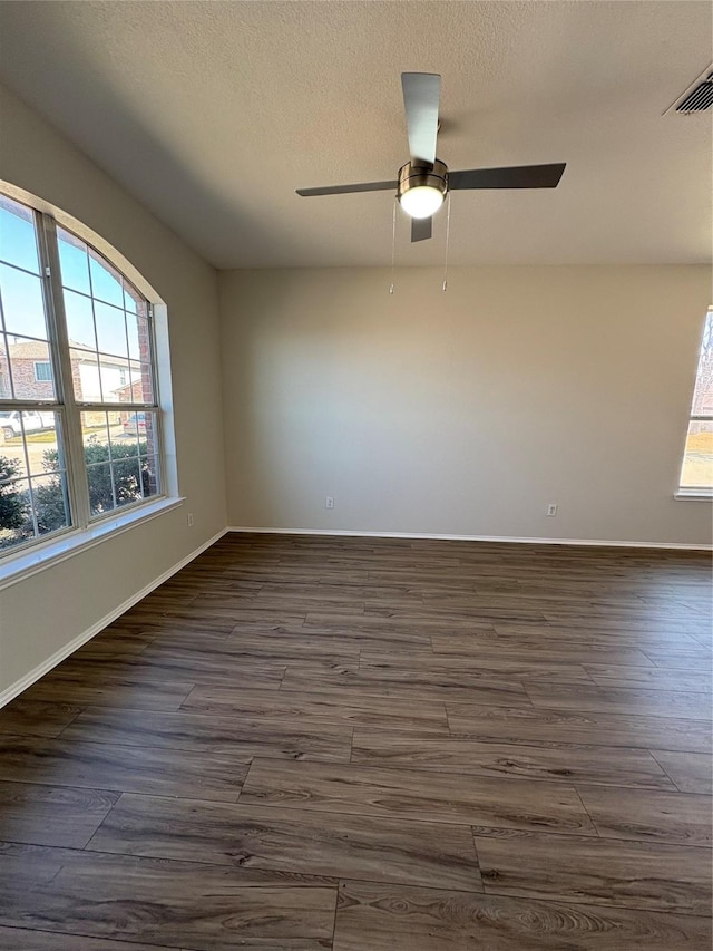 unfurnished room featuring a textured ceiling, dark wood-style flooring, visible vents, and baseboards