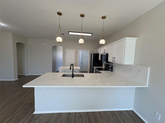 kitchen featuring arched walkways, light stone counters, a peninsula, a sink, and black appliances