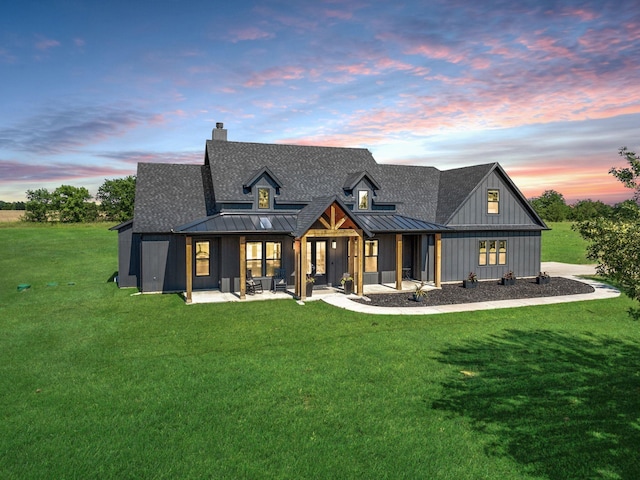 back house at dusk with a lawn and a patio