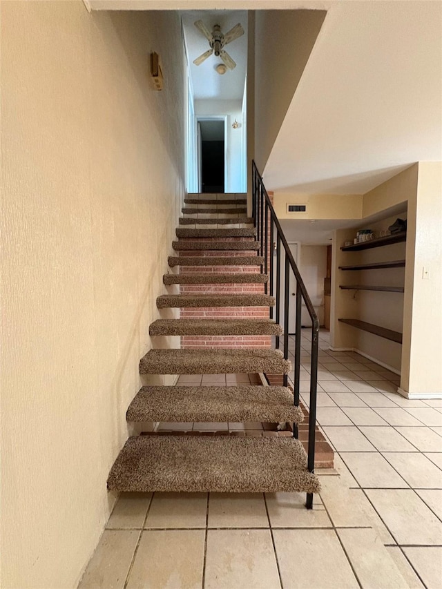 stairs featuring tile patterned floors and ceiling fan