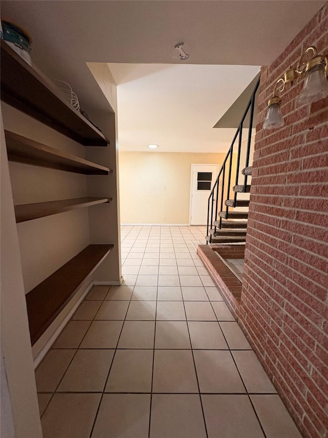 corridor featuring brick wall and tile patterned floors