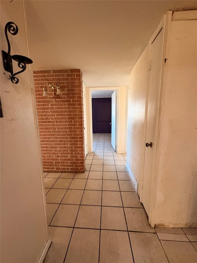 corridor with brick wall and light tile patterned floors