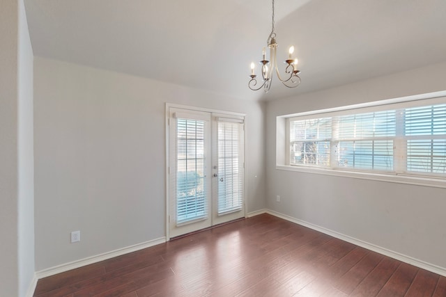 spare room with a chandelier, dark hardwood / wood-style floors, and french doors