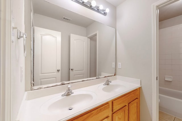 bathroom with tiled shower / bath, tile patterned floors, and vanity