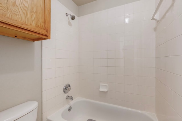 bathroom featuring toilet and tiled shower / bath