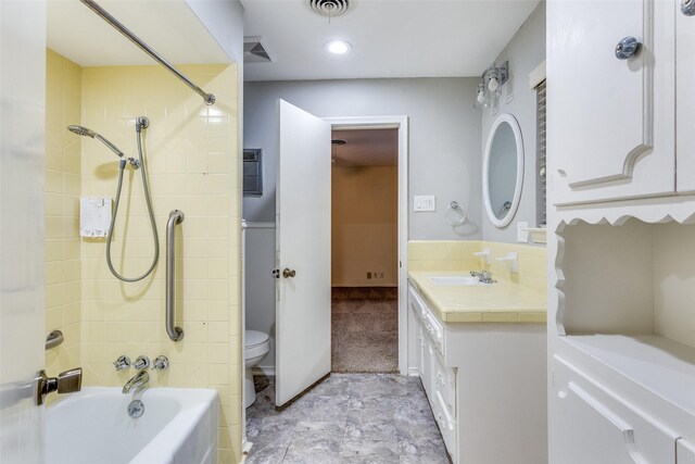 bathroom with tile walls, vanity, and shower / washtub combination