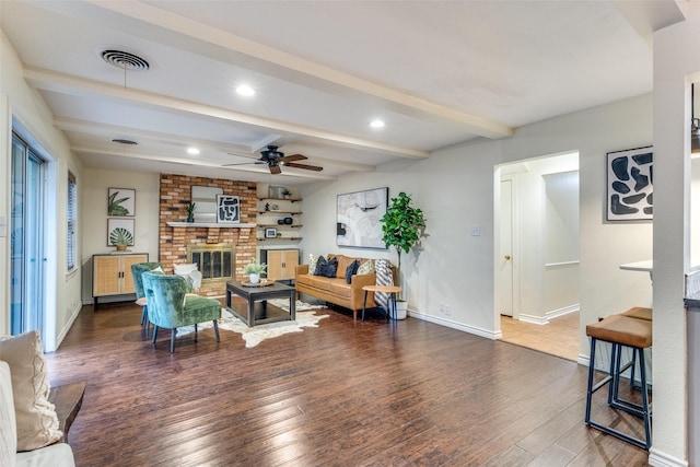 living room with beamed ceiling, ceiling fan, dark hardwood / wood-style floors, and a brick fireplace