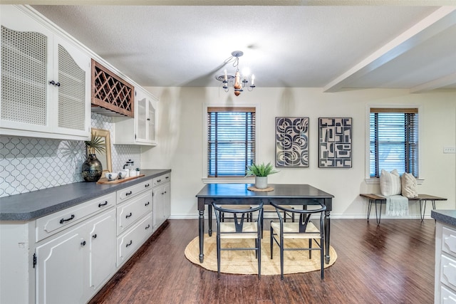 dining area with a textured ceiling, dark wood-type flooring, a chandelier, and a wealth of natural light