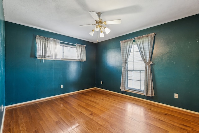 empty room featuring ceiling fan, hardwood / wood-style floors, and a wealth of natural light