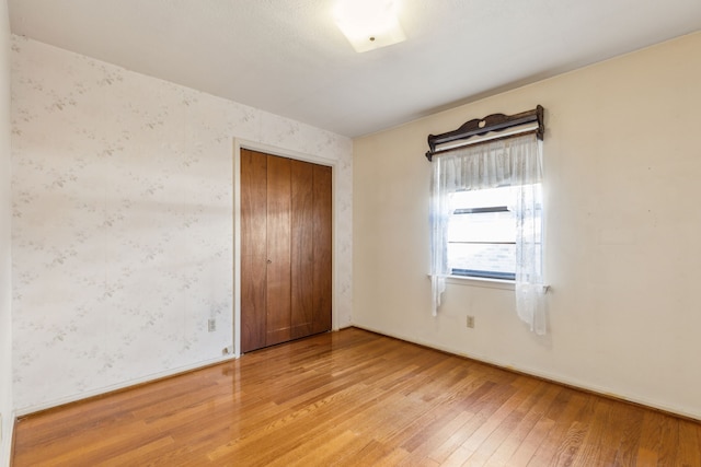 unfurnished bedroom featuring light wood-type flooring and a closet