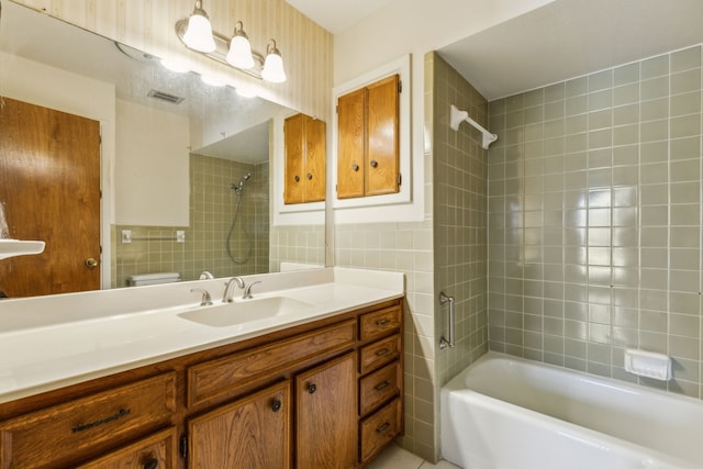 full bathroom featuring tiled shower / bath, tile patterned flooring, vanity, tile walls, and toilet