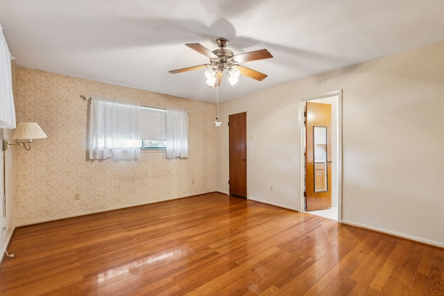 unfurnished bedroom with ceiling fan, wood-type flooring, and ensuite bathroom