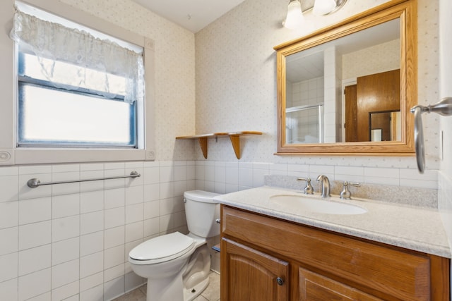 bathroom featuring a shower with door, tile walls, toilet, and vanity