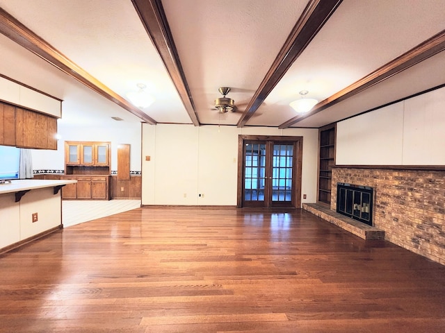 unfurnished living room with light wood-type flooring, french doors, beam ceiling, and built in features