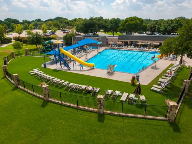 view of swimming pool featuring a patio area, a water slide, and a lawn