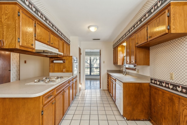 kitchen with sink, white appliances, light tile patterned floors, and decorative backsplash