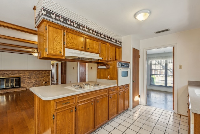 kitchen with light tile patterned flooring, white appliances, kitchen peninsula, and a fireplace