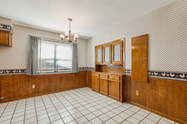 kitchen featuring a notable chandelier, wood walls, pendant lighting, and light tile patterned flooring