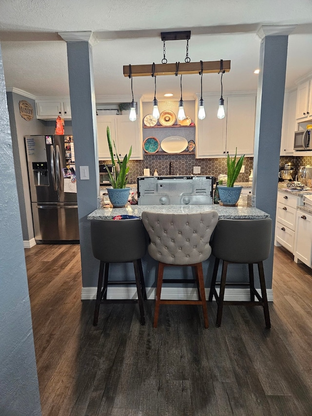 kitchen with white cabinetry, a kitchen breakfast bar, decorative light fixtures, stainless steel appliances, and dark hardwood / wood-style floors