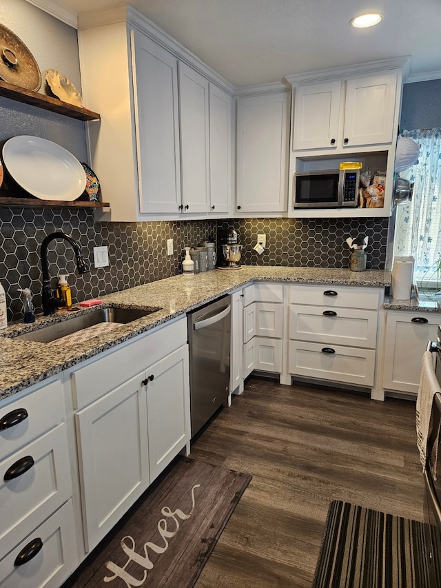 kitchen with appliances with stainless steel finishes, sink, white cabinets, light stone counters, and ornamental molding