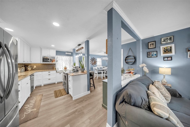 kitchen featuring appliances with stainless steel finishes, white cabinetry, backsplash, light stone counters, and light hardwood / wood-style floors