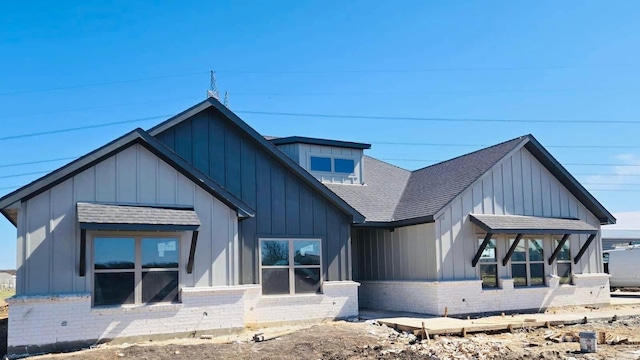 view of front facade featuring board and batten siding, brick siding, and a shingled roof