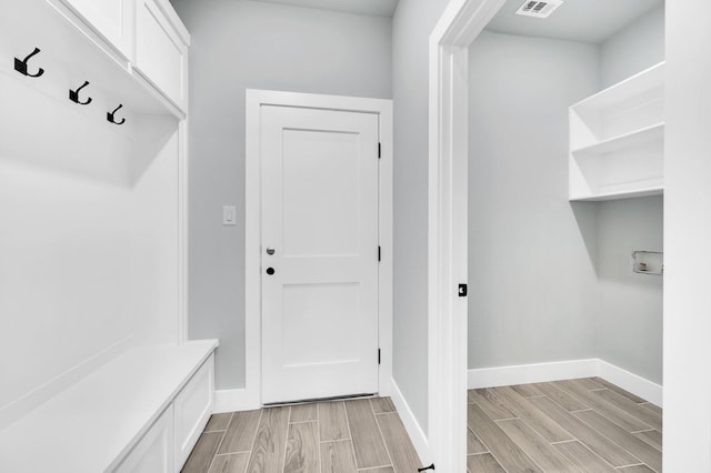 mudroom with visible vents, wood finish floors, and baseboards