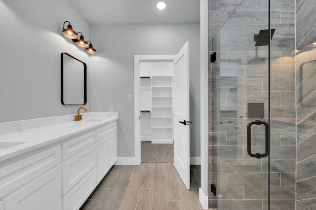 bathroom with recessed lighting, a sink, a shower stall, double vanity, and a spacious closet
