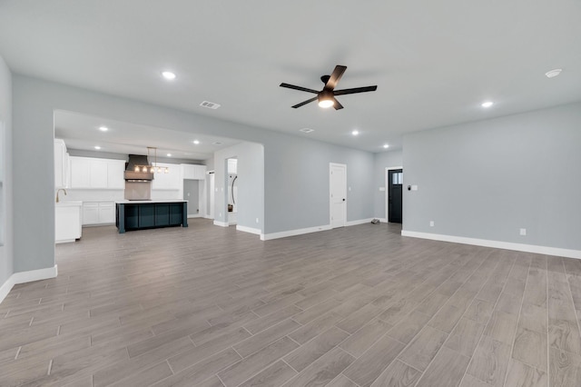 unfurnished living room featuring baseboards, visible vents, ceiling fan, and light wood-style flooring