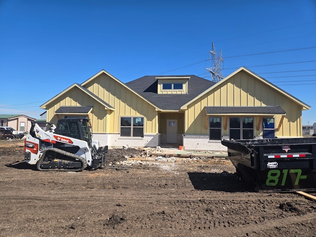 view of front of house with brick siding, board and batten siding, and roof with shingles