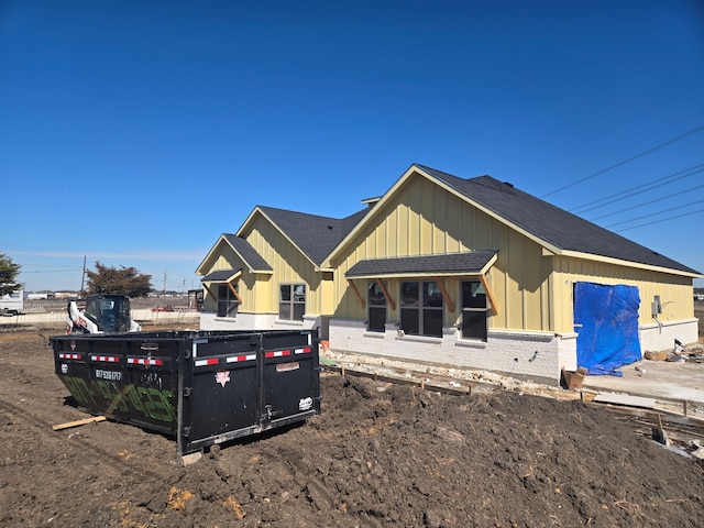 view of front of home with brick siding, board and batten siding, and a shingled roof