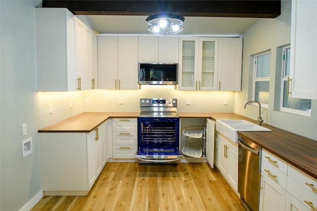 kitchen with sink, wooden counters, appliances with stainless steel finishes, light hardwood / wood-style floors, and white cabinets