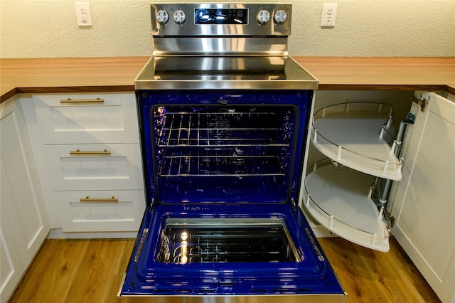 details with white cabinetry, wood-type flooring, butcher block countertops, and electric stove