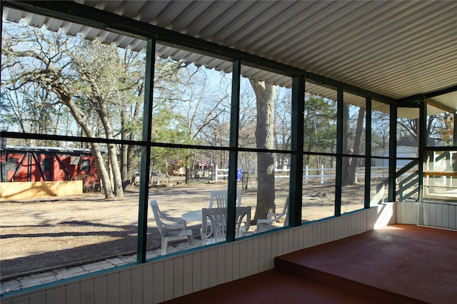 unfurnished sunroom featuring lofted ceiling with beams and a healthy amount of sunlight