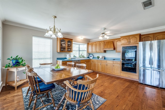 kitchen with custom exhaust hood, decorative light fixtures, stainless steel appliances, hardwood / wood-style flooring, and crown molding