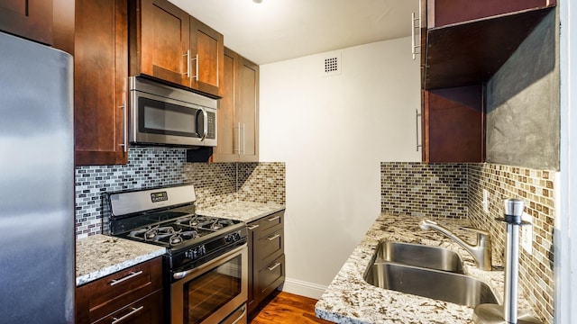 kitchen featuring sink, light stone countertops, appliances with stainless steel finishes, and decorative backsplash