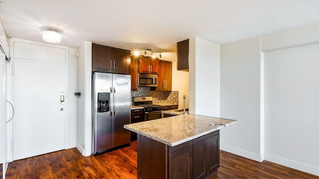 kitchen featuring appliances with stainless steel finishes, tasteful backsplash, kitchen peninsula, dark hardwood / wood-style flooring, and light stone counters