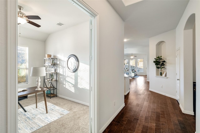 corridor with lofted ceiling, wood finished floors, visible vents, and baseboards