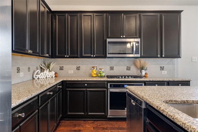 kitchen featuring light stone countertops, appliances with stainless steel finishes, dark hardwood / wood-style floors, and backsplash