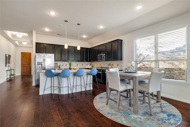 kitchen featuring pendant lighting, dark wood-type flooring, backsplash, stainless steel appliances, and a center island