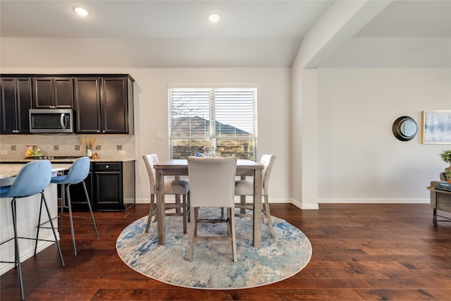 dining room with dark hardwood / wood-style floors and vaulted ceiling