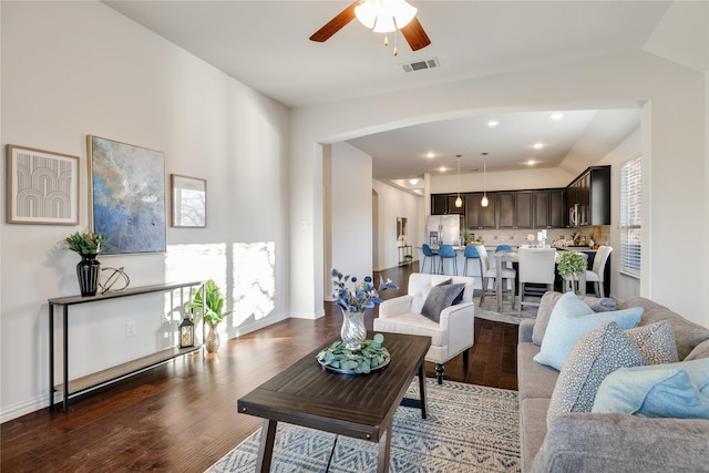 living room featuring ceiling fan, dark hardwood / wood-style floors, and vaulted ceiling